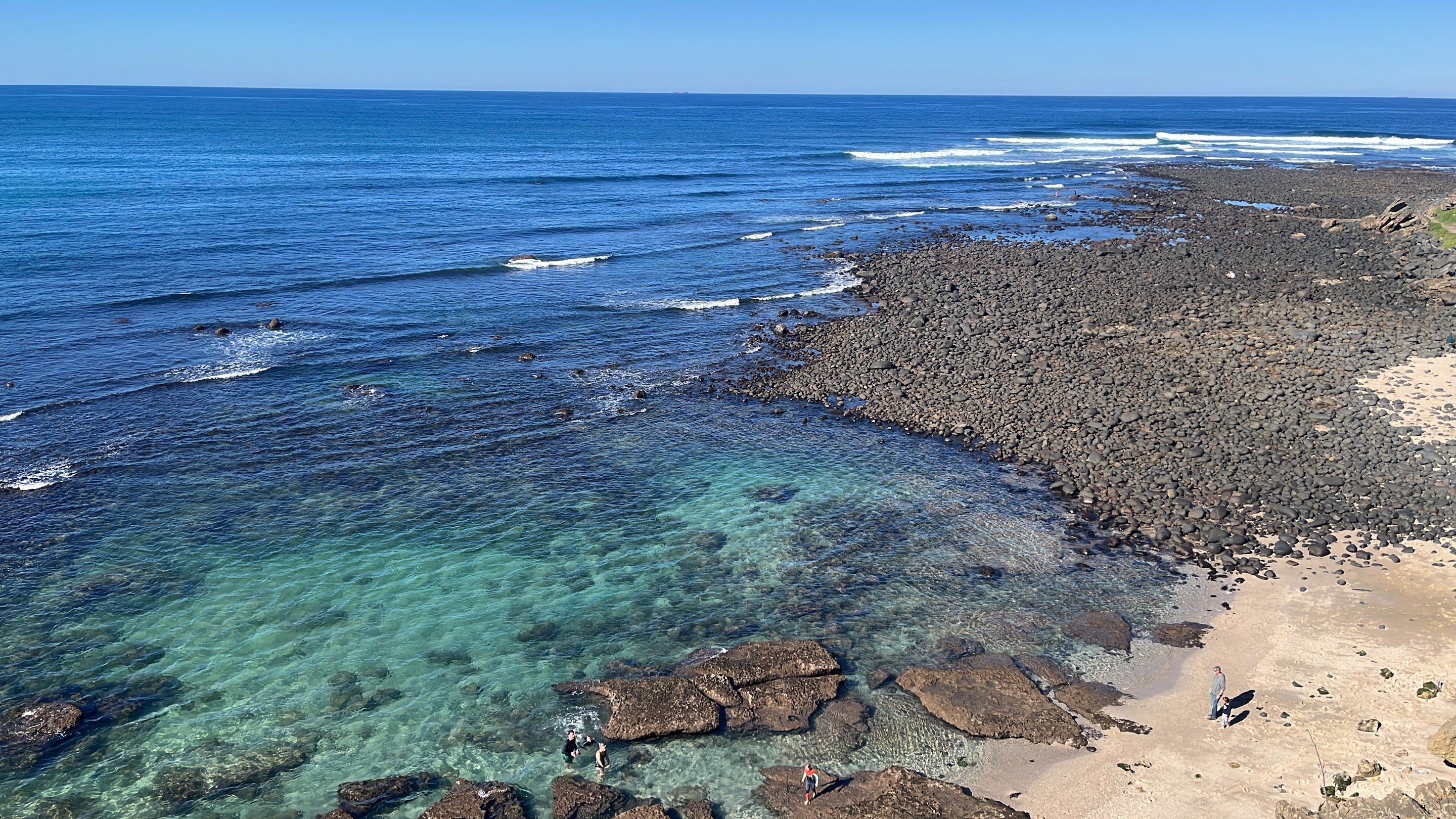 Rock pools and clear turquoise water below a pebble shore on the Eastern Cape coast